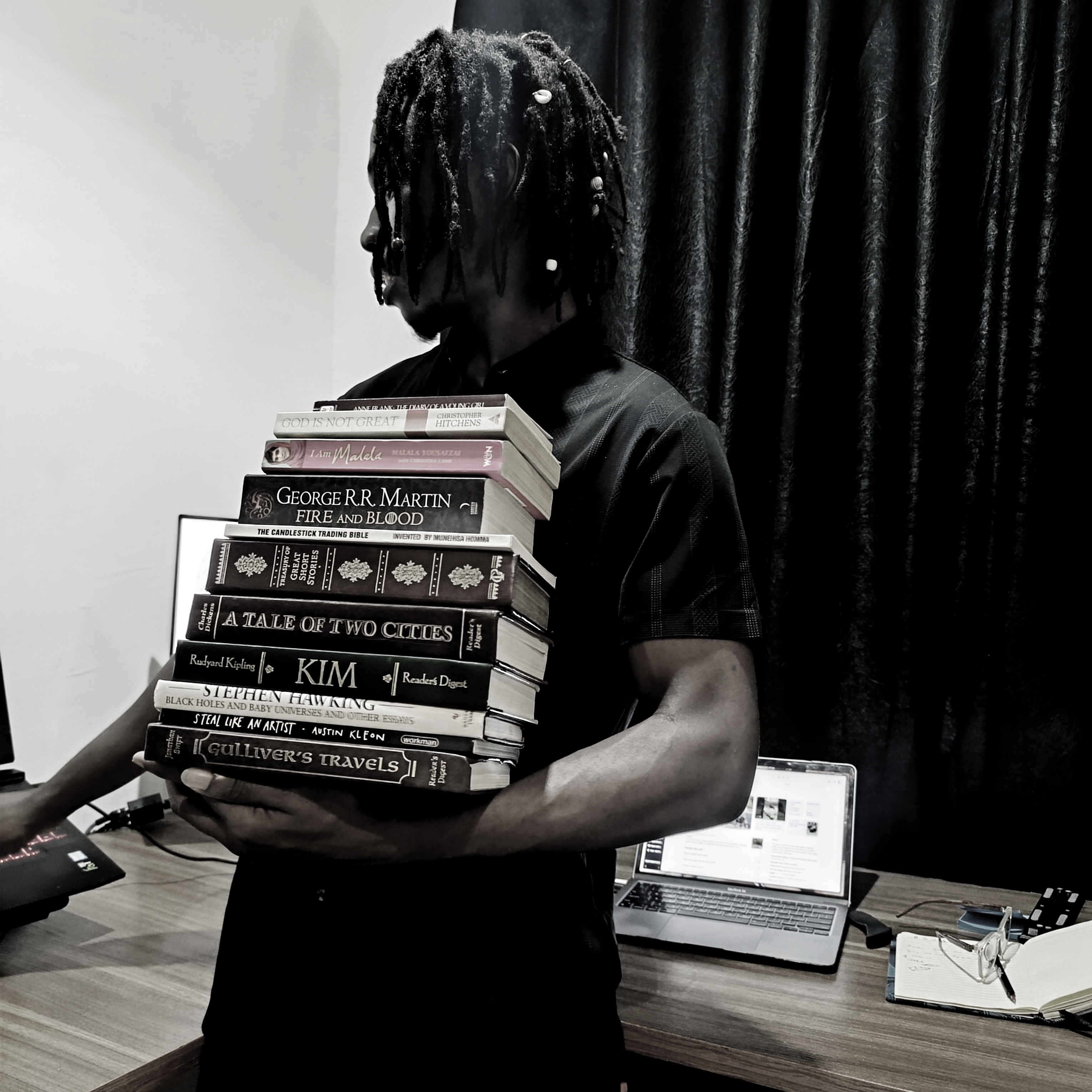 A picture of me holding a stack of classic books in my workspace at home